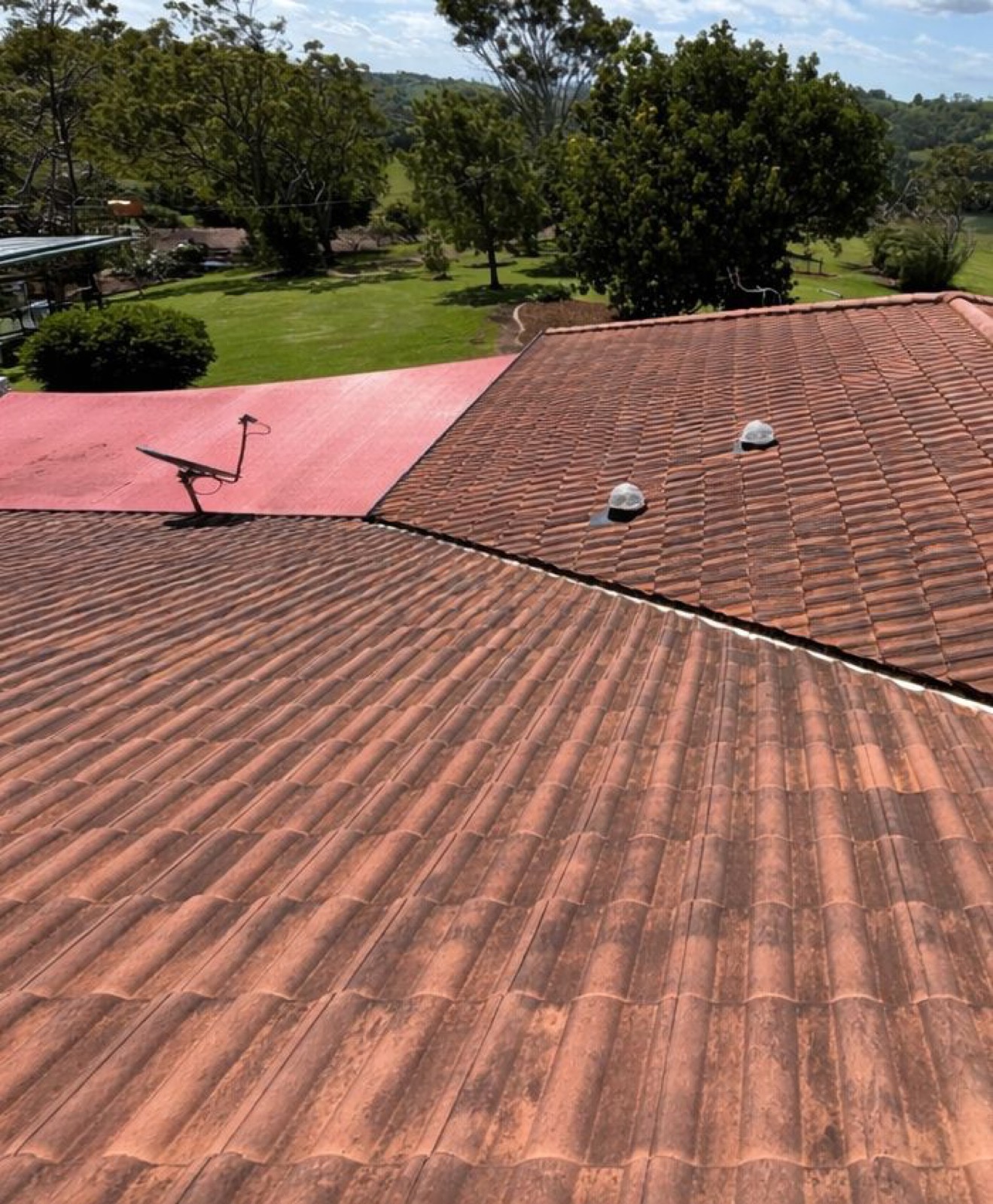 A moss and lichen covered terracotta tile roof on a rural property