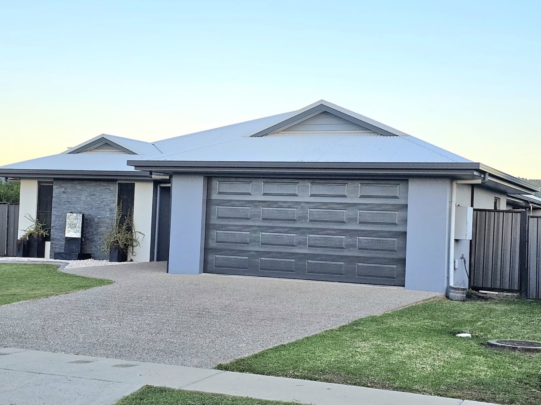 A house with dark timber-look garage doors at dusk