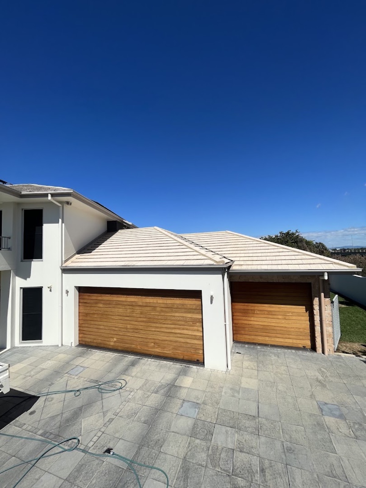 A two-storey rendered home with timber-look garage doors