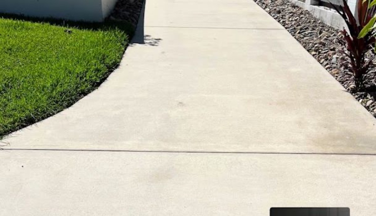 A clean concrete path beside a garden bed