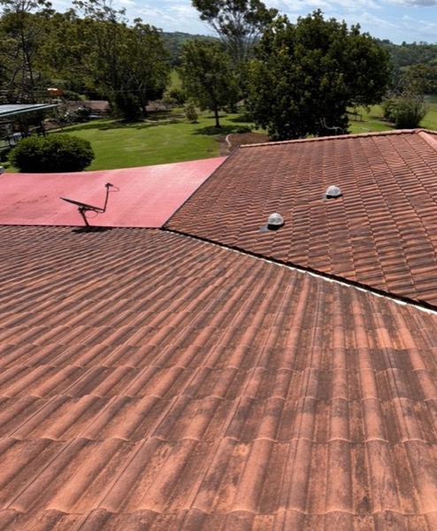 An aerial view of a two-tone tile roof beside a grassed valley