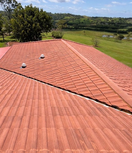 An aerial view of a terracotta tile roof with green hills in the distance