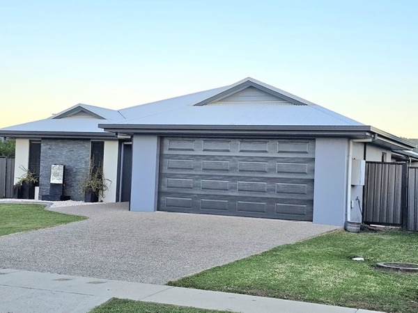 A two-storey house with dark grey garage doors at dusk