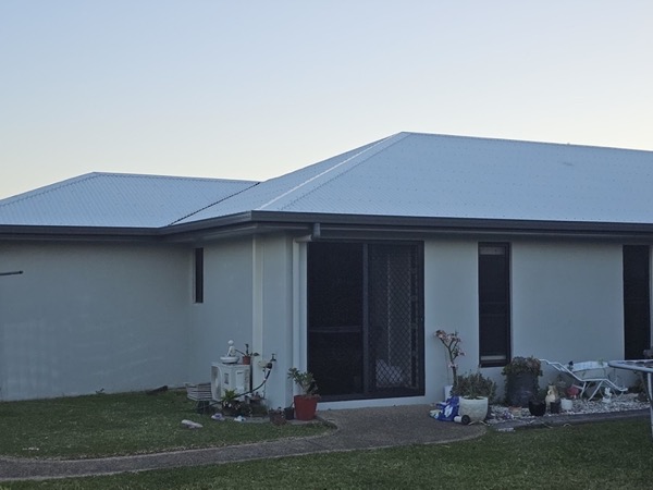 A single-storey house exterior with a sliding glass door at dusk
