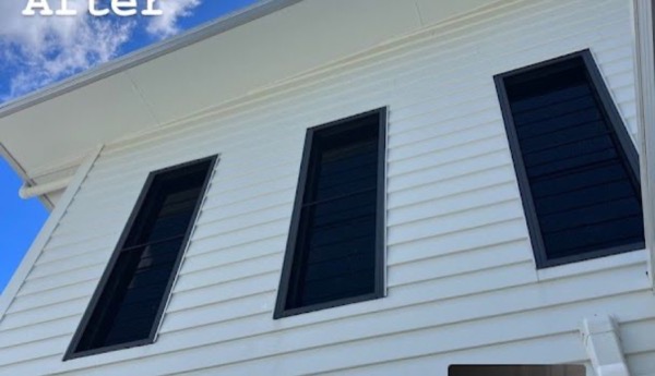 Tall exterior windows on a white weatherboard house seen from below