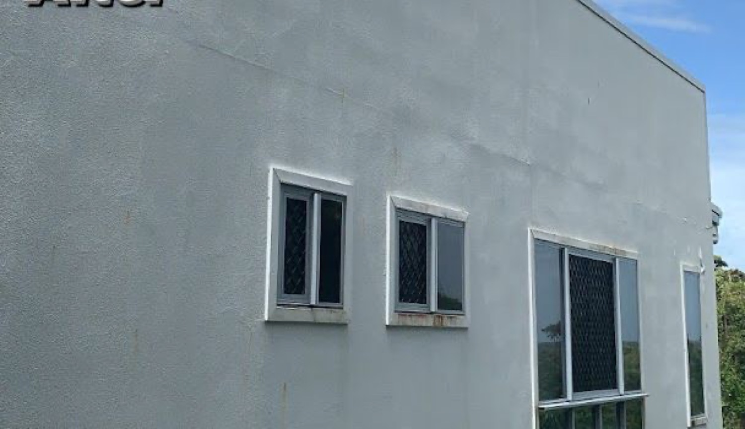 A pale rendered house wall and window