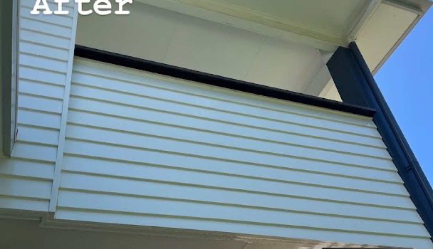 A pale blue-grey rendered wall corner beside black roof trim